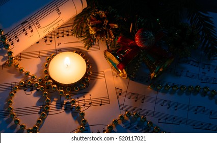 Christmas Decorations, Burning Candle And Sheet Music In The Dark