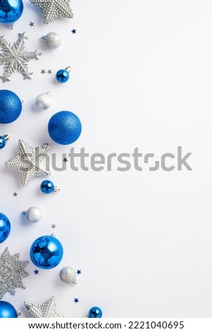 Christmas decorations concept. Top view vertical photo of blue white silver baubles snowflake star ornaments and confetti on isolated white background with copyspace