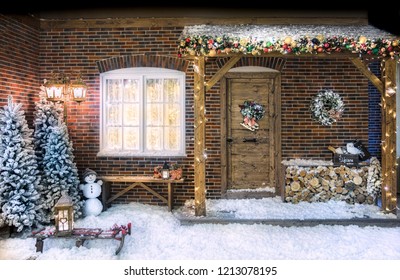 Christmas decorations front of the house with Christmas trees, firewood, a bench, a wreath, a snowman and slay - Powered by Shutterstock