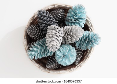 Christmas decorations, top view of a group of large colored pine cones inside a wicker basket, isolated on white background - Powered by Shutterstock