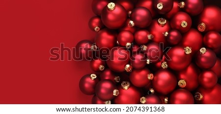 Christmas decorations, top view of pile of glass balls colored in red, isolated on red background, useful as a greeting gift card template