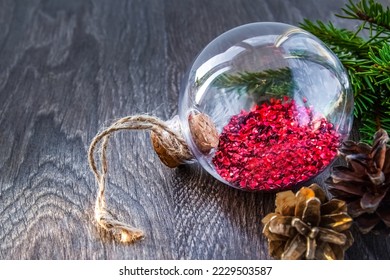 Christmas decorations with transparent glass ball , spruce branch and cone on table