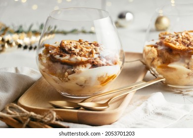 Christmas dessert in glasses made up of baked apple, crunchy almond cookies, custard, jam, yogurt, cinnamon, and toasted almonds. Parfait - Powered by Shutterstock