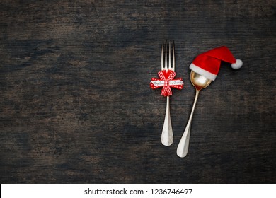 Christmas Dining Concept Background. Christmas Table Place Setting With Vintage Silverware Set Of Cutlery Fork, Spoon In Santa Red Hat, Top View, Flat Lay. Christmas Decorative Outfit, Minimal Design