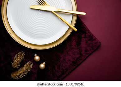 Christmas Dinner Plate Decoration With Golden Xmas Ornaments On Purple Background. Merry Christmas Card. Winter Holiday Theme. Happy New Year. Flat Lay. 