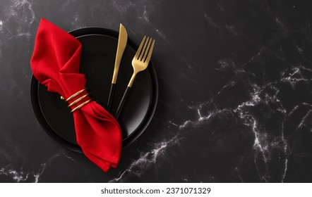 Christmas dinner at a restaurant. Top view of festive plates, exquisite gold flatware, red napkin with ring on luxurious black marble table with text space - Powered by Shutterstock