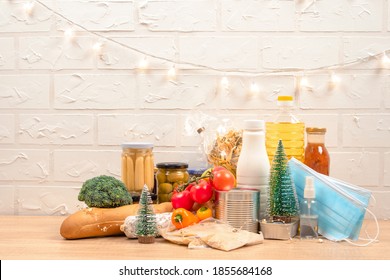 Christmas Donation Box - Food Donations On Light Background With Copyspace - Pasta, Fresh Vegatables, Canned Food, Baguette, Cooking Oil With Christmas Decorations. Food Bank. Selective Focus