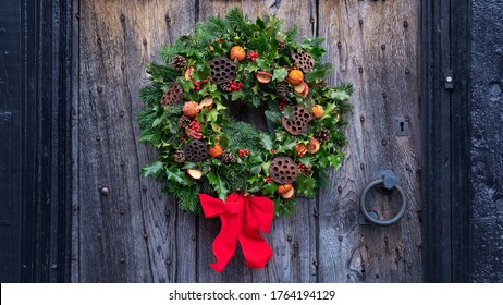 Christmas door wreath, a natural arrangement of flowers, berries, fruits and leaves fasten on a ring and set on a house entrance door as decoration, a winter holidays symbol of unending circle of life