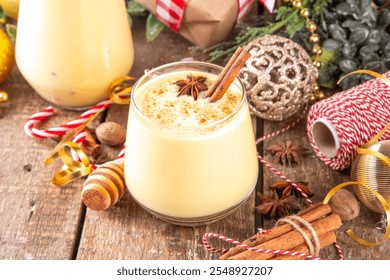 Christmas drink with cinnamon sticks and anise stars, two glasses of sweet classic eggnog cocktail on Christmas, New Year decorated background with fir tree and baubles - Powered by Shutterstock