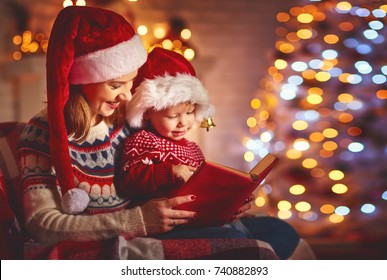 Christmas Eve. Family Mother And Baby Reading Magic Book At Home Near The Fireplace And The Christmas Tree
