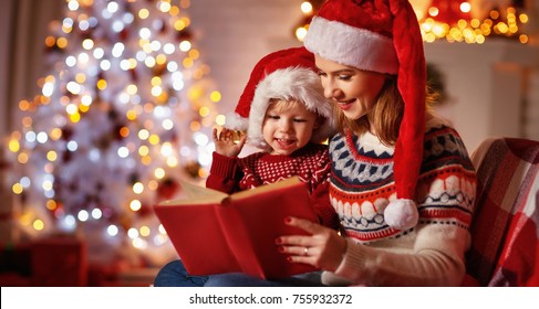 Christmas Eve. Family Mother And Baby Reading Magic Book At Home Near The Fireplace And The Christmas Tree