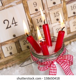 Christmas eve: four red burning candles with a shabby white advent calendar background