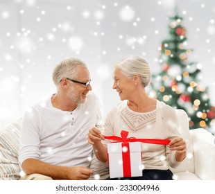 christmas ,family, holidays, age and people concept - happy senior couple with gift box and snow - Powered by Shutterstock