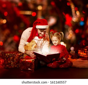 Christmas Family Reading Book. Father And Child Opening Magic Fairy Tale Over Red Background.