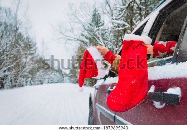 christmas family travel by car, family with santa\
hat and socking on road in\
snow
