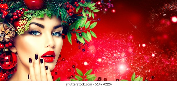 Christmas Fashion Model Woman. Xmas New Year Hairstyle And Make Up. Beauty Girl Portrait. Gorgeous Vogue Style Lady With Christmas Decorations On Her Head, Baubles, Professional Makeup, Red Background