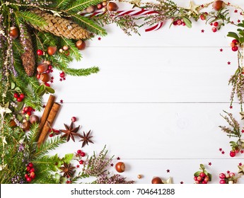 Christmas fir tree and heather decoration, fir cones and red berries, cinnamon sticks and star anise spices on a white wooden background - Powered by Shutterstock