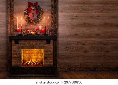 Christmas fireplace in a festive interior of a Log Cabins with wooden walls. Mantelpiece with candles, Christmas wreath with bells and bow - Powered by Shutterstock
