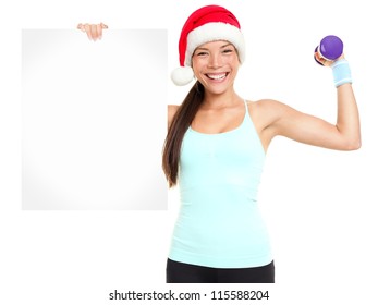 Christmas Fitness Woman Showing Sign Standing With Red Santa Hat Isolated On White Background. Fit Smiling Happy Fitness Model Of Mixed Asian Chinese And Caucasian Ethnicity.