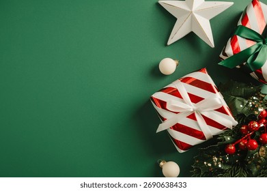 Christmas flat lay frame, composition with gifts boxes and festive stars, baubles over green background