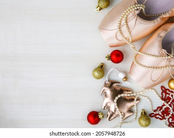 Christmas flat lay pair of pink Pointe Shoes, tree, golden and red balls, red star, pearl beads on white wooden background. Christmas concept, top view, copy space