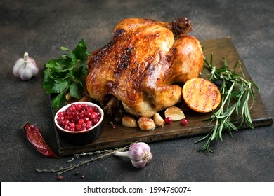 Christmas food. Fried chicken with orange, cranberries, garlic and rosemary on a dark background. Festive table with Christmas decorations. - Shutterstock ID 1594760074