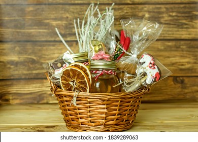 Christmas Food Gift Baskets. Edible Christmas Gift Made Of Cookies, Honey, Homemade Handmade Sweets, Dried Oranges, Lollipops On A Wooden Table.Concept Handmade Christmas Gifts, Handmade Food Presents