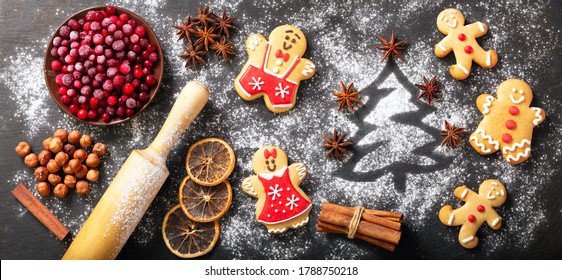 Christmas food. Ingredients for Christmas baking:  fir tree made from flour, kitchen utensils, frozen cranberries and gingerbread cookies on a dark table, top view - Powered by Shutterstock