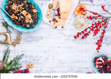 Christmas Food In Italy For The Holiday. Pasta Is Black With Seafood And Various Snacks, Wine And Parmesan Cheese. Top View And Light Wooden Background