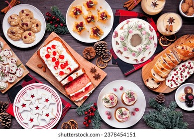 Christmas food table scene. Top down view on a dark wood background. Assorted appetizers and delicious sweets. Copy space. Holiday party food concept.