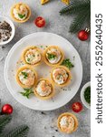 Christmas food. Tartlets with shrimp, cream cheese, garlic and parsley on a wooden board on gray concrete background