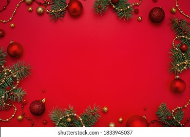 Christmas frame of fir tree and decorations on red background. Copy space, holiday flat lay.
