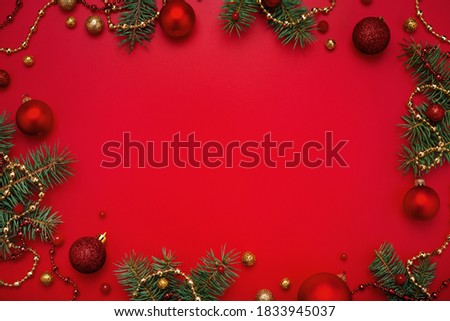 Christmas frame of fir tree and decorations on red background. Copy space, holiday flat lay.