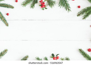Christmas frame made of fir branches, red berries. Christmas wallpaper. Flat lay, top view, copy space