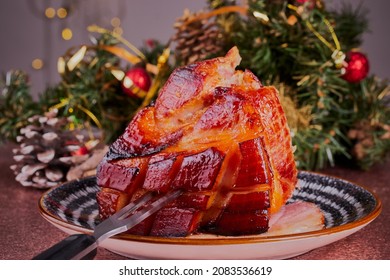 Christmas gammon roast joint resting on a plate, with Christmas decorations in the background.