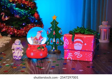 Christmas Gift Box Next to a Festive Christmas Tree and a Glass Snow Globe with Santa Claus Inside. Perfect Scene for Christmas and New Year Greetings - Powered by Shutterstock