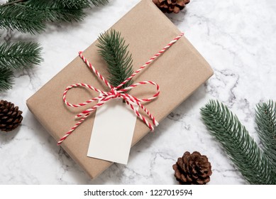 Christmas gift box with note card and tree branch decor on marble background. Flat lay, Top view with copy space