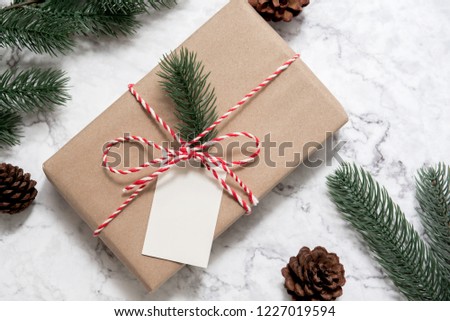 Christmas gift box with note card and tree branch decor on marble background. Flat lay, Top view with copy space