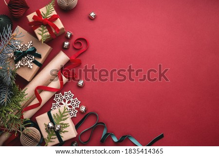 Christmas gift boxes, velvet ribbons, rolls of wrapping paper and decorations on red background.