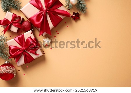 Christmas gift boxes with vibrant red bows, Christmas ornaments, and pine branches on a warm beige backdrop
