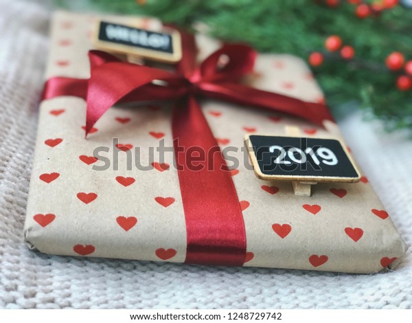 christmas gift\
craft box with hearts and red ribbon and hello 2019 chalkbords.\
rustic new year 2019\
flatlay