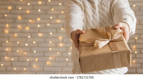 Christmas Gift In Man Hands Holiday Wallpaper Poster Concept Picture With White Wall Background And Garland Illumination Lamps 
