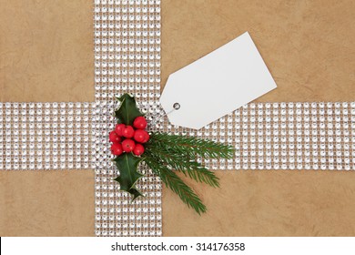 Christmas Gift Wrapping With Diamond Bling Ribbon, Tag And Holly Over Hemp Paper Background.