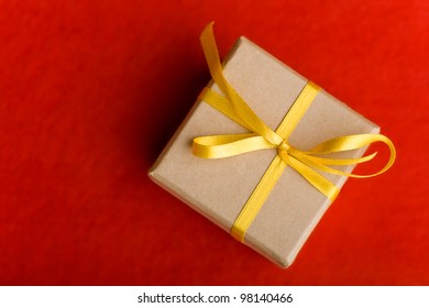 Christmas Gift With Yellow Bow From Above On A Red Background