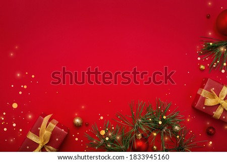 Christmas gifts, fir tree and gold decorations on red background. Copy space, flat lay.