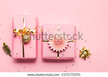Christmas gifts wrapped in pink tissue paper and Christmas ornaments  on a pink background 