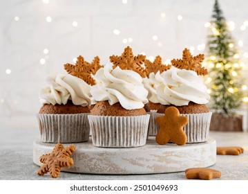 Christmas gingerbread cupcakes with cream cheese frosting and mini gingerbread cookies on top on a wooden board. Festive dessert - Powered by Shutterstock