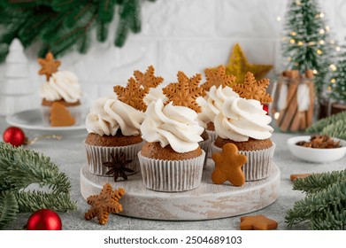 Christmas gingerbread cupcakes with cream cheese frosting and mini gingerbread cookies on top on a wooden board. Festive dessert - Powered by Shutterstock