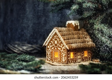 Christmas Gingerbread House with Window Lights in Winter Snowy Forestat Night. Creative Food Decoration Design for Xmas Holiday over Dark Background with Copy Space - Powered by Shutterstock
