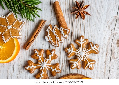 Christmas gingerbread and sweets are placed on wooden desk. Cookies and sweet food in shape of stars and snow flakes. Winter theme, rustic style. Pine trees on the side. Candy stick and other spice.